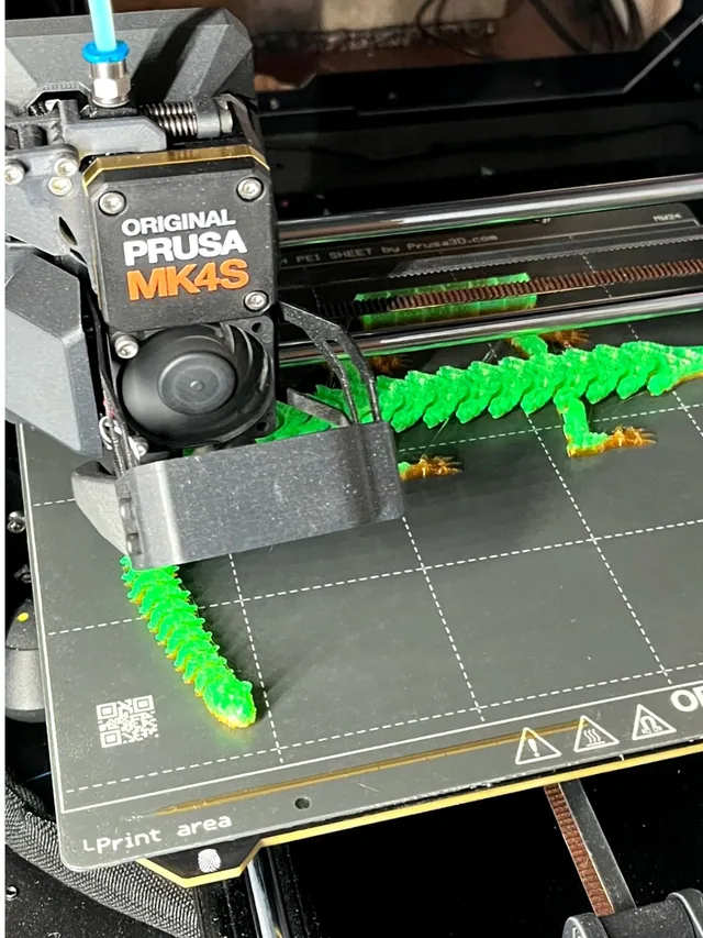 Druckkopf eines Prusa MK4S, der gerade eine grüne Gelenk-Echse druckt